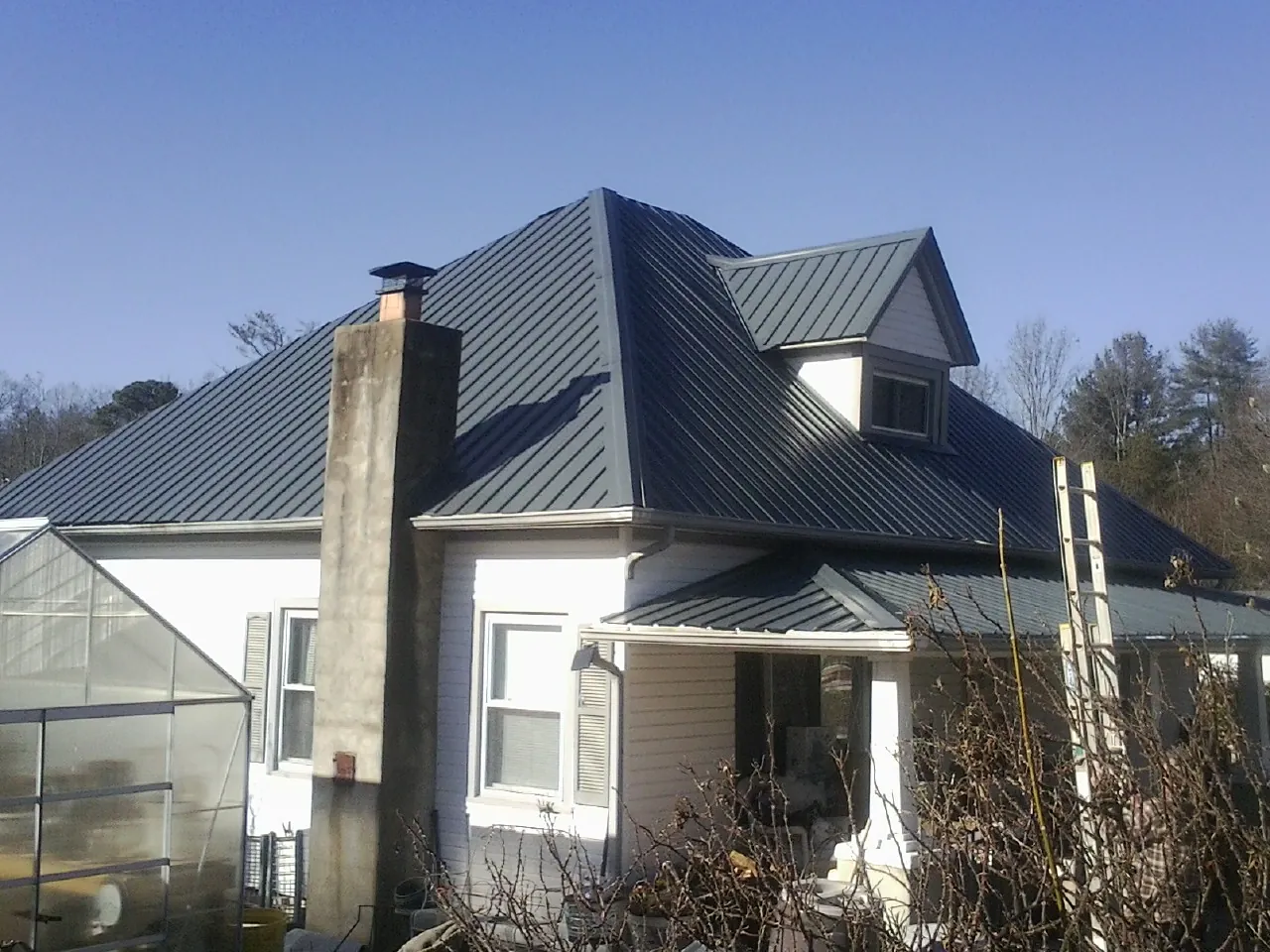 Dark blue standing seam metal roof on a white farmhouse with dormer — Slate & Tile Roof Repair by Roofing Brothers in Morehead