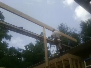 Carpenter setting a ridge beam over a new addition frame — Ice Dam Removal by Roofing Brothers in Morehead