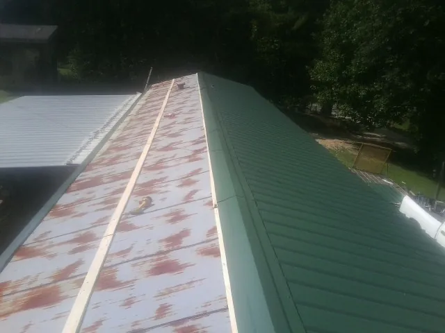Old rusted panels beside newly installed green metal roofing — Wind Damage Roof Repair by Roofing Brothers in Morehead