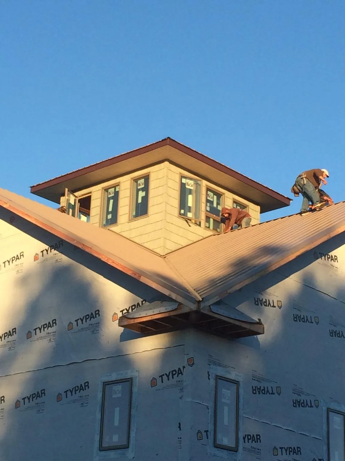 Roofers working around a rooftop cupola on a new metal roof at sunset — Roof Waterproofing in Morehead by Roofing Brothers